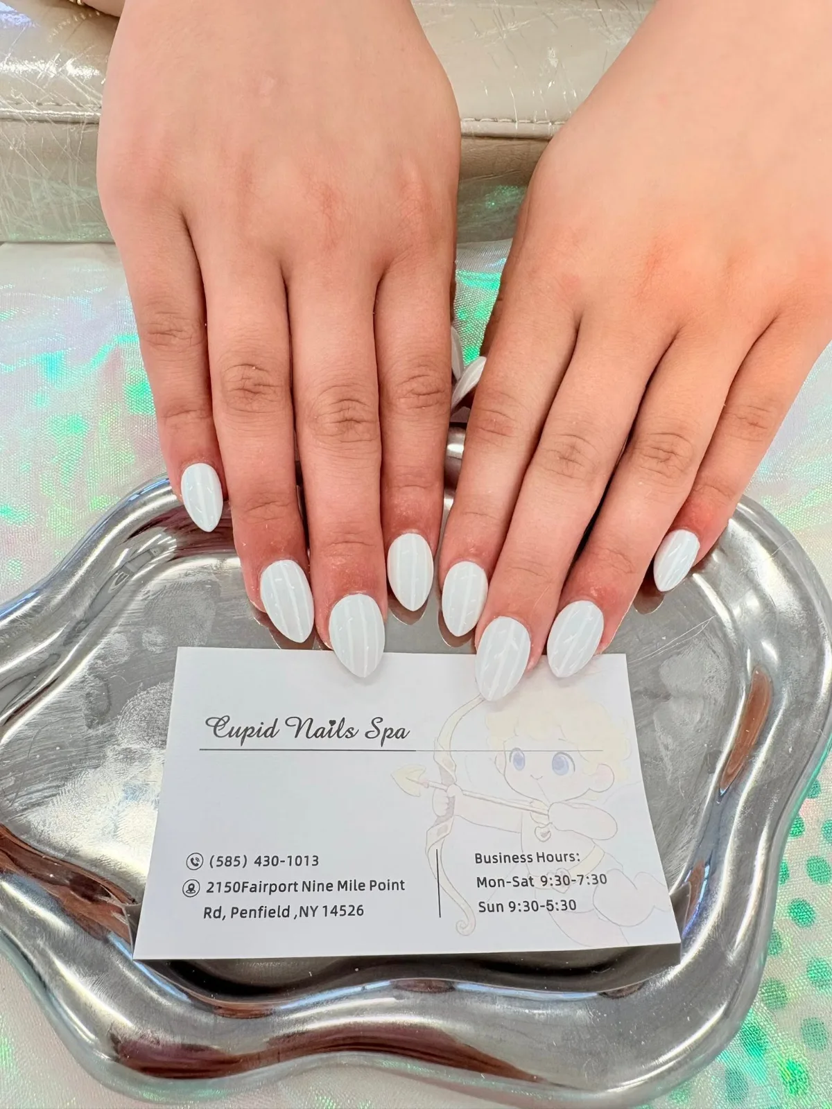 Almond nails in glossy opaque white, both hands resting on a silver tray
